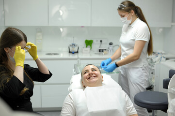 Fototapeta premium Positive delighted woman sitting in cabinet of her dentist while doing checkup. High quality photo