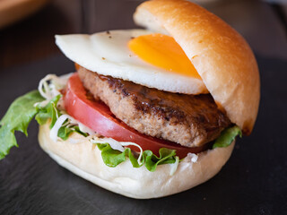 肉のパテと目玉焼きとトマトとキャベツを挟んだハンバーガーパン。