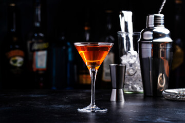 Bobby Burns alcoholic cocktail drink with scotch whiskey, vermouth and liquor in martini glass, dark bar counter background
