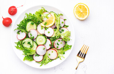 Healthy summer salad with fresh radishes, cucumbers, lettuce and green onion with greek yogurt dressing, white table background, top view