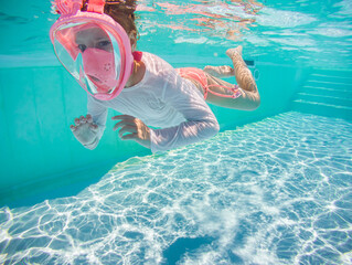 Little girl snorkeling underwater in the pool. Learning child to swim and diving.