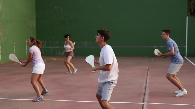 Group of sporty young people paleta fronton player hitting ball with a racket