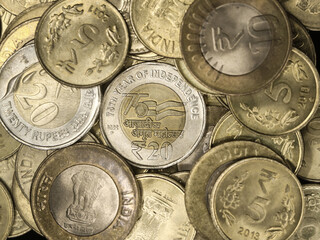 closeup shot of a rare indian 20 (twenty) rupees coin gold and silver, a symbol of 75 year of independence celebration, on a pile of other authentic collection of indian coins