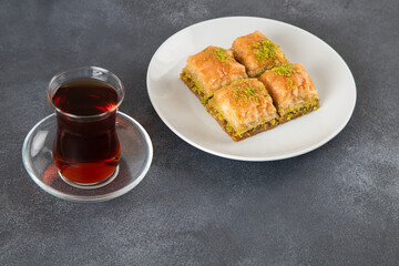 Traditional pistachio baklava with Turkish tea.A plate of baklava black background