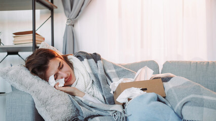 Home fever. Sick woman. Unhealthy girl wrapped plaid laying sofa with napkin influenza symptoms...