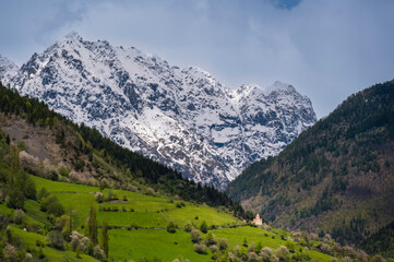 Church in the green grass mountains with snow mountains background