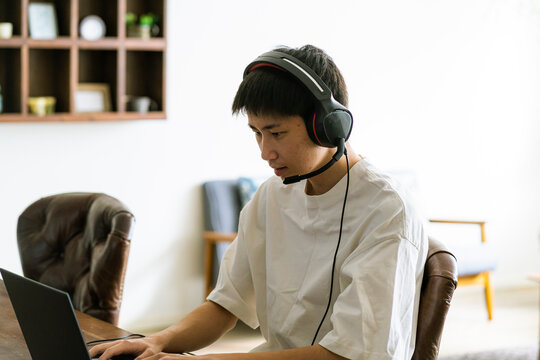 インカムを着けてパソコンを見る若い日本人男性