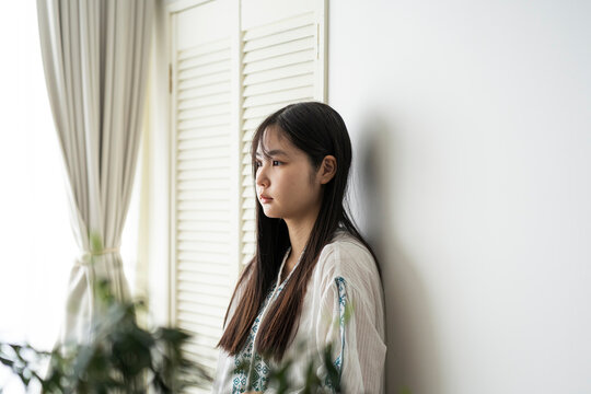 壁に寄り掛かる若い日本人女性