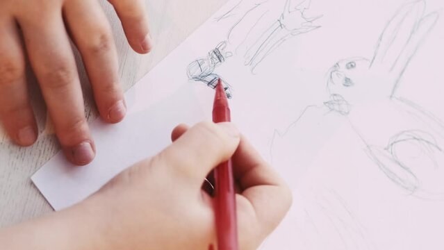Creative picture. Kids painting. Art hobby. Unrecognizable child drawing on white paper with pencil sitting table.