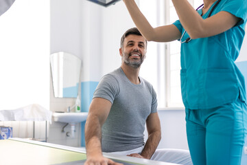 Obraz premium Female radiologist preparing patient for X-ray of hand near X-ray machine. Radiologist Taking X-ray Of Patient Lying On Gurney