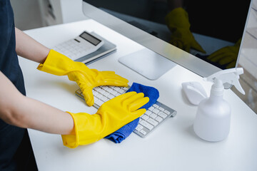 Young woman using a computer keyboard cleaning cloth to disinfect the office.office cleaning staff cleaning maid