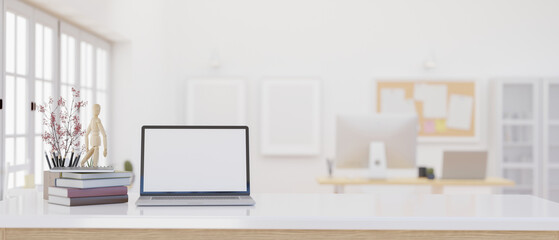 Fototapeta premium A laptop mockup on a white table over blurred background of a modern bright office.
