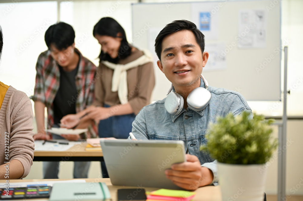 Canvas Prints a male worker in a tech startup team sits at a table with a tablet in his hand
