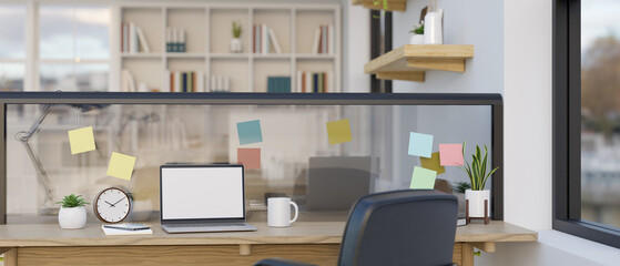 Modern office workspace with laptop mockup on a table, sticky notes on a table glass partition