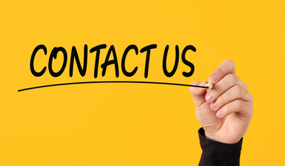 Contact us concept. Male hand draws a line under the word contact us on yellow background.