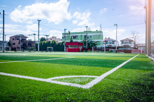 Artificial turf soccer field, a corner marker line, green background. Outdoor field.