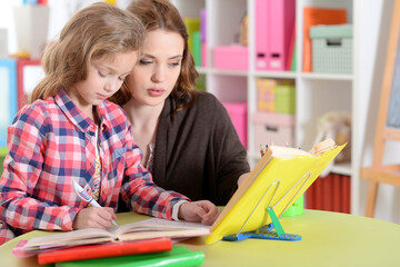 Cute little girl with her mother doing homework