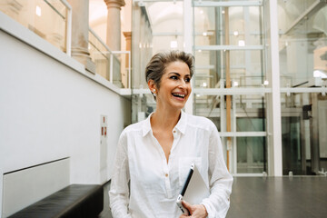 Smiling mature woman manager holding tablet while working in art gallery