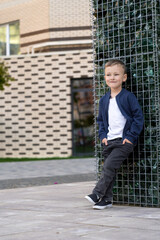 Cute little boy in white T-shirt and black romper posing on front of column of glass stones. Portrait of fashionable male child. 