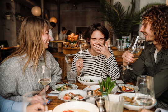 Group of friends drinking wine while dining in restaurant