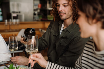 Group of friends talking and drinking wine while having dinner in restaurant