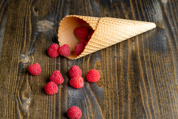 Red ripe raspberries with waffle cups on a black table