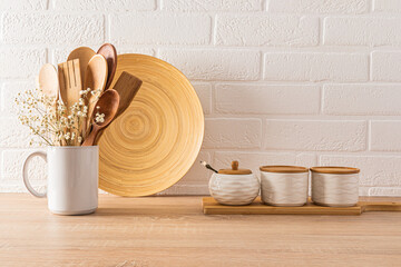 Ceramic jars with bamboo lid and sugar bowl, mug with wooden spoons on wooden countertop in the interior of a modern eco-friendly kitchen.
