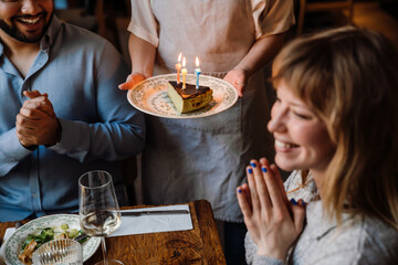 Cheerful blonde woman celebrating birthday in restaurant