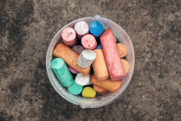 Top view of colorful drawing chalk sticks in plastic bucket