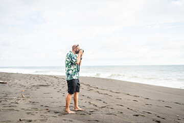 Man taking photos with digital camera on a sandy beach