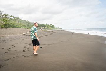 Man walking along a remote beach with a camera