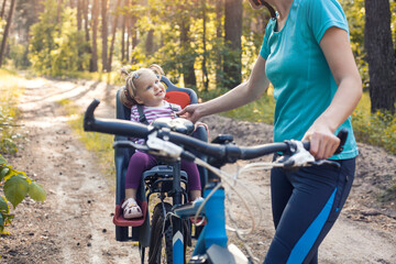 Fototapeta na wymiar mom and baby ride a bike in a summer pine forest