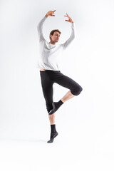 One Caucasian Handsome Young Man Dancing Ballet Posing in Dance Pose with Lifted hands in White Shirt On White.