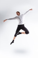 Fototapeta na wymiar One Professional Caucasian Handsome Young Athlete Man Posing in Flying Ballet Pose with Lifted Hands in White Shirt On White.