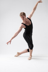 Sports Ideas. Young Athletic Caucasian Ballet Dancer Man Posing in Stretching Pose With Hands Lifted in Line and Knees Bended in Black Tights