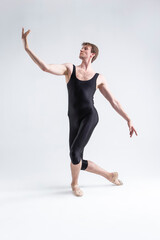 Fototapeta na wymiar Young Athletic Caucasian Ballet Dancer Man Posing in Stretching Pose With Hands Lifted in Line and Knees Bended in Black Tights On White.