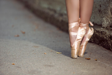 Female Ballet Dancer Legs In Laced Pointes Shoes While Posing With Straight Legs Outdoors On Tile...