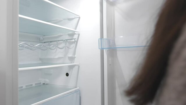 Woman Opens And Closes Door Of Empty Fridge. closeup