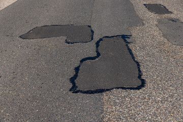 The repaired part of an asphalt road with patches
