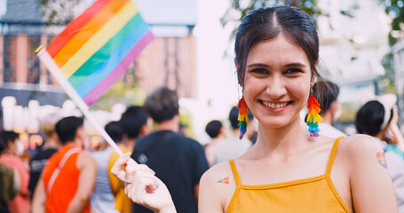 A young woman with rainbow tattoo stickers and showing symbols of homosexuality in pride parade.