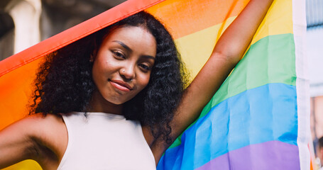 A young black woman waves a rainbow flag, a symbol of homosexuality, during a pride parade.