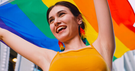 A young woman waves a rainbow flag, a symbol of homosexuality, during a pride parade.