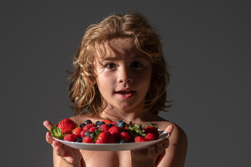 Child boy hold plate of mix summer fruits. Healthy organic strawberry fruit, summer season.