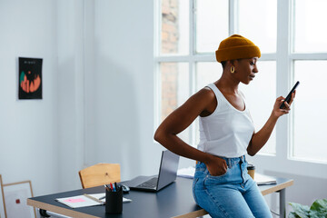 Freelancer with hand in pocket using smart phone at office