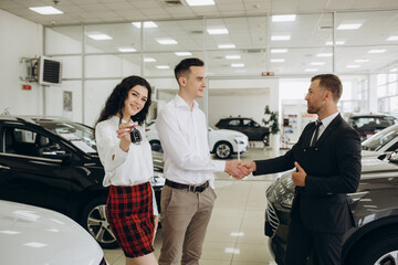 Car dealer showing car to couple in showroom