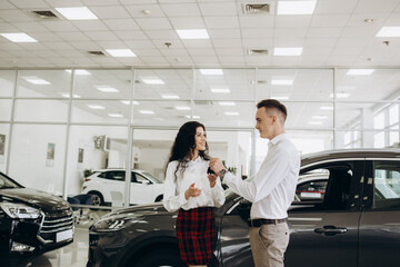 Young couple buying a car in the showroom
