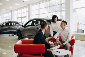 Happy caucasian couple signs a contract for the purchase of a car salon.