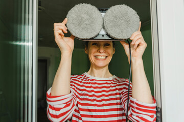 Happy woman holding window washer over face