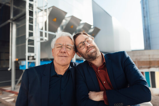 Businessmen with eyes closed at industrial building