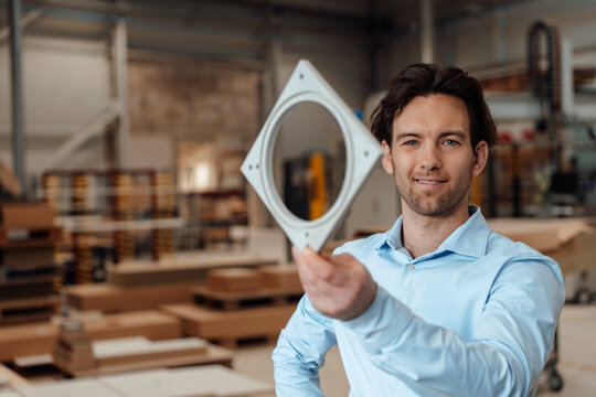 Smiling businessman with machine part in industry